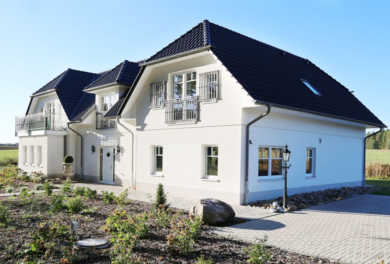 Großes Haus mit Balkon und gepflasterten Parkplätzen