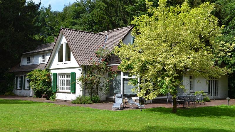 Landhaus mit grünen Fensterläden in parkähnlicher Umgebung